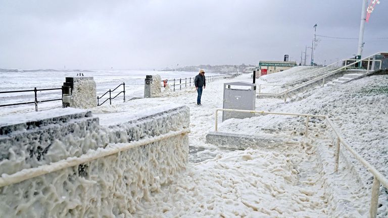 A man walks through sea foam in Seaburn, Sunderland,  as Storm Babet batters the country 