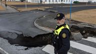 A police officer stands by the crack in a road in the fishing town of Grindavik, which was evacuated due to volcanic activity, in Iceland 