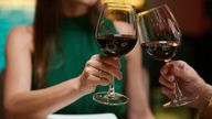 Cropped image of couple clinking glasses of red wine when having romantic date in restaurant