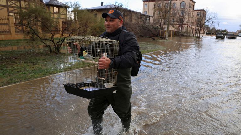 A man carries a cage with a parrot while walking along a flooded street following a storm in Yevpatoriya, Crimea 