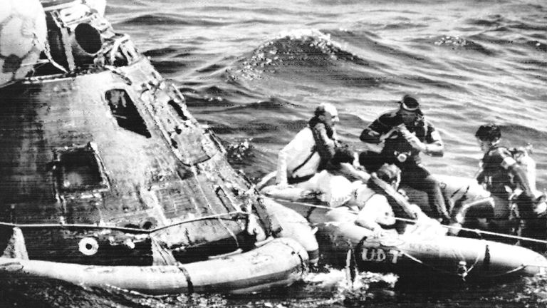Apollo 16 astronauts, from left wearing white suits, Thomas Mattingly, John Young and Charles Duke, pose for photographs by Navy Frogmen in rubber raft after leaving spaceship, left, in the Pacific Ocean on Thursday, April 27, 1972. The successful splashdown of their spacecraft was made precisely on time, within one mile of the recovery ship, USS Ticonderoga. (AP Photo)


