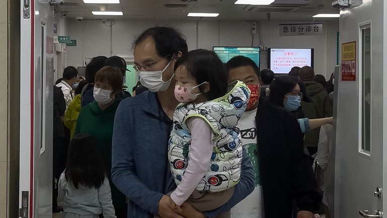 A man carriers a child walk out from a crowded holding room of a children&#39;s hospital in Beijing on Oct. 30, 2023