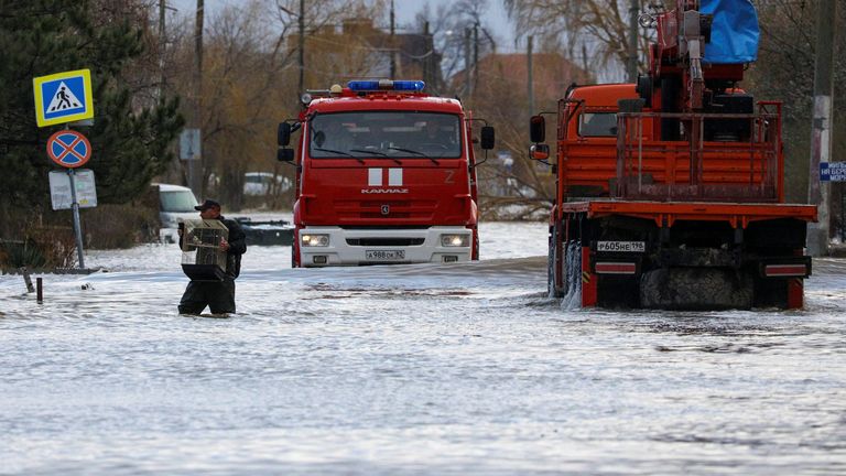 Trucks drive past a man carrying a cage with a parrot in a flooded street following a storm in Yevpatoriya, Crimea, November 27, 2023. REUTERS/Alexey Pavlishak
