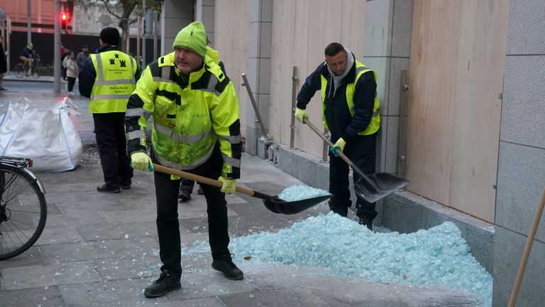 Workers clean up the debris from broken windows