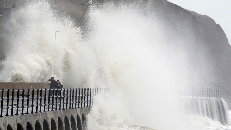 People run away from crashing waves at the promenade in Folkestone, Kent