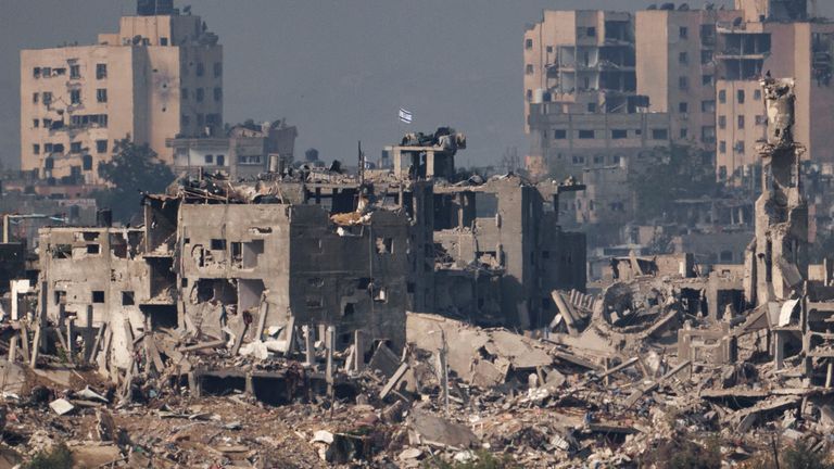 An Israeli flag stands on the top of a destroyed building in northern Gaza