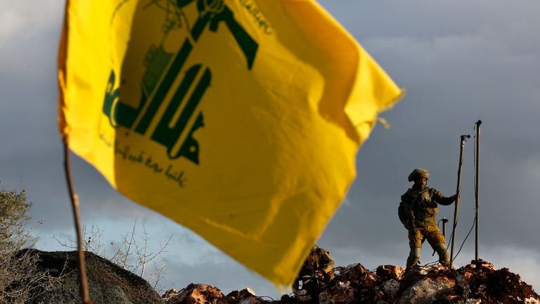 An Israeli soldier sets up cameras at their new position in front of a Hezbollah flag, near the Lebanese southern border village of Mays al-Jabal, Lebanon, Thursday, Dec. 13, 2018. As Israeli excavators dig into the rocky ground, Lebanese across the frontier gather to watch what Israel calls the Northern Shield operation aimed at destroying attack tunnels built by Hezbollah. But Lebanese soldiers in new camouflaged posts, behind sandbags, or inside abandoned homes underscore the real anxiety tha