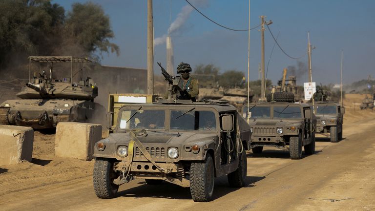 Israeli military vehicles move along a road at Israel&#39;s border with Gaza