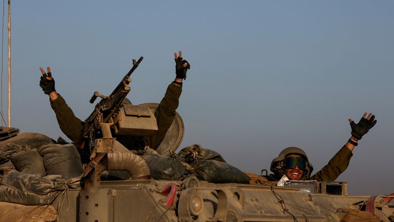 Israeli soldiers gesture from a military vehicle while driving by Israel&#39;s border after leaving Gaza during the temporary truce between the Palestinian Islamist group Hamas and Israel, in Israel, November 24, 2023. REUTERS/Amir Cohen