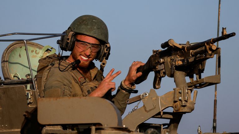 An Israeli soldier gestures from a military vehicle while driving by Israel&#39;s border after leaving Gaza during the temporary truce between the Palestinian Islamist group Hamas and Israel, in Israel, November 24, 2023. REUTERS/Amir Cohen