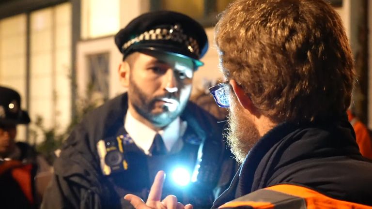 Police officer stands listening to a Just Stop Oil protester in London