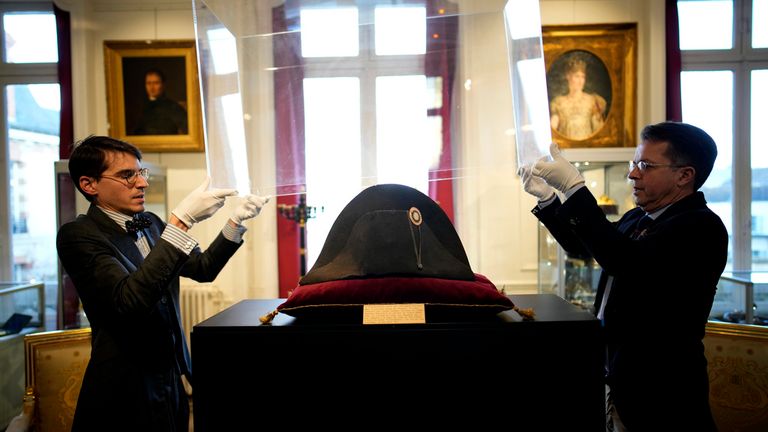 Raphael Pitchal, left, and Jean Christophe Chataignier of Osenat&#39;s auction house remove the protection of one of the signature broad, black hats that Napol..on wore when he ruled 19th century France and waged war in Europe at Osenat&#39;s auction house in Fontainebleau, south of Paris, Friday, Nov. 17, 2023. The hat is tipped to fetch more than half a million euros (dollars) at the auction Sunday of Napoleonic memorabilia patiently collected by a French industrialist. (AP Photo/Christophe Ena)