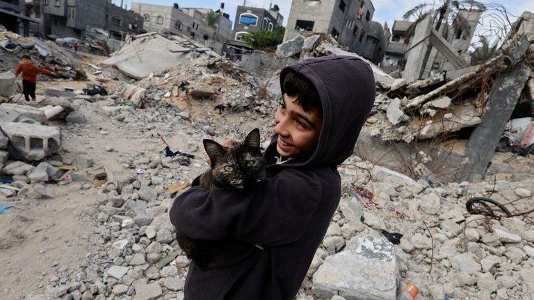 A Palestinian child holds a cat, while standing on the rubble of houses destroyed in Israeli strikes during the conflict, amid the temporary truce between Hamas and Israel, at Khan Younis refugee camp in the southern Gaza Strip November 27, 2023. REUTERS/Mohammed Salem
