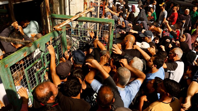 Palestinians queue as they wait to buy bread from a bakery, amid shortages of food supplies and fuel  in Khan Younis in the southern Gaza Strip