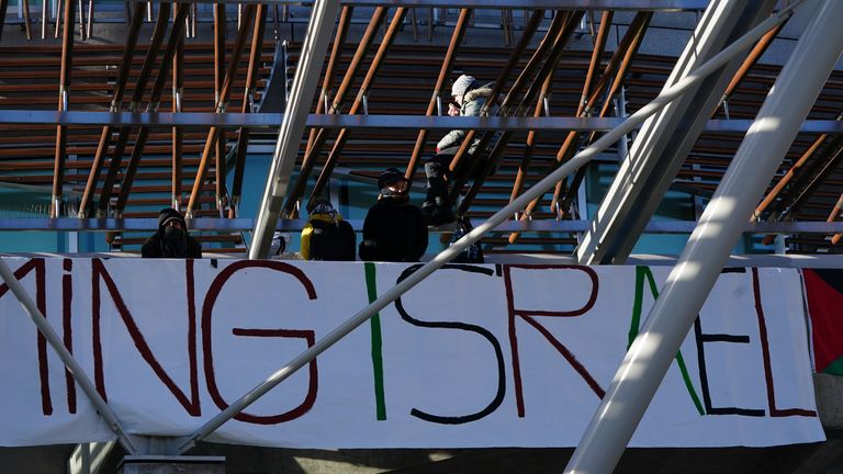 Pro-Palestinian protesters on the roof of the Scottish Parliament in Holyrood, Edinburgh, after hanging a banner and the Palestinian flag. The group of five climbed up the awning outside the main entrance on Thursday morning, unfurling a banner which reads "Stop arming Israel". Police have cordoned off the area underneath but business in the Parliament is continuing. Picture date: Thursday November 9, 2023.