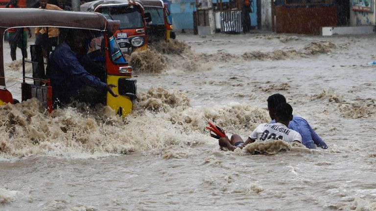 A man attempts to rescue a boy from raging flood waters following heavy rains in Mogadishu, Somalia