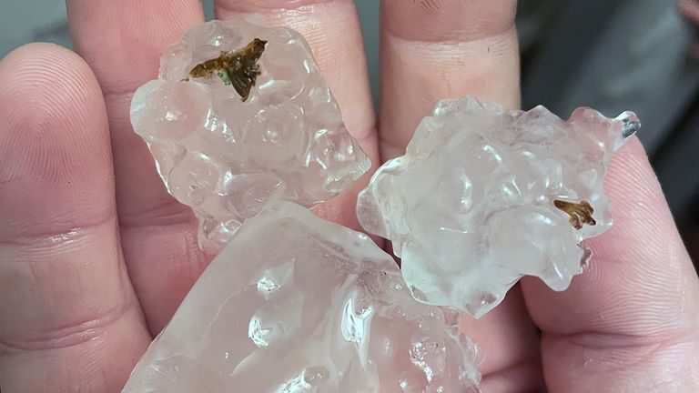 A man holds large pieces of ice which fell in a hail storm in St Helier, Jersey 