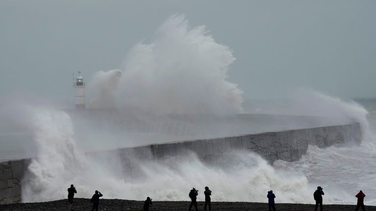 Waves crash over Newhaven Lighthouse and the harbour wall in Newhaven