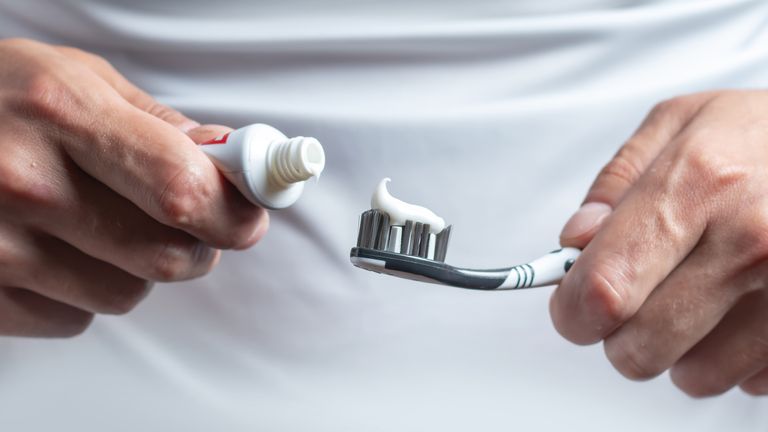 A man is preparing to brush his teeth, squeezing out the paste on the brush (file photo)