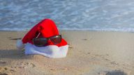 Christmas and New Year on the beach by the sea while relaxing and traveling to warm countries. Red Santa Claus hat with sunglasses on the sand by the sea. iStock
