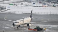 A snowplough drives past a plane as Munich Airport has cancelled all incoming and outgoing flights 