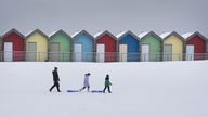 People walk through the snow beside the beach huts at Blyth in Northumberland, as temperatures are tipped to plunge to as low as minus 11C in parts of the UK over the weekend. Picture date: Sunday December 3, 2023.