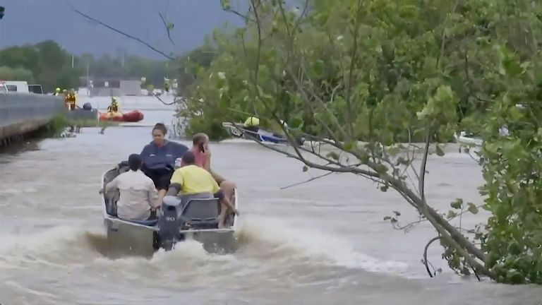 People ride boats on a flooded river in Cairns. Pic: AP
