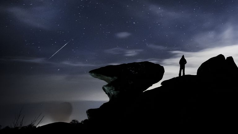 A man watches a meteor during the Geminid meteor shower over Brimham Rocks, a collection of balancing rock formations in the Nidderdale Area of Outstanding Natural Beauty in North Yorkshire.