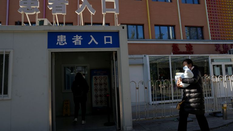 A visitor carries a child into the children&#39;s hospital with a sign "Patient entrance" in Beijing, 24 November, 2023. Pic: AP