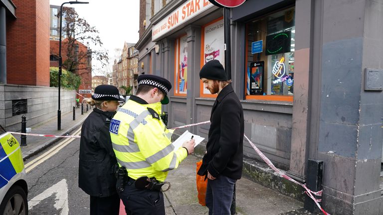 Metropolitan Police officers speak to a man beside a cordon at a property in Cranwood Street