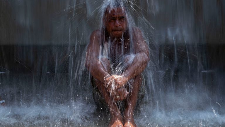 A man cools off in a water fountain at Madureira Park amid a heat wave in Rio de Janeiro, Brazil. Pic: AP