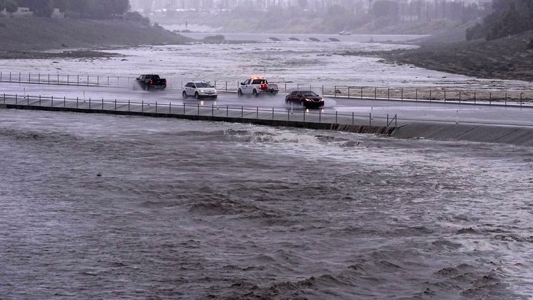 Vehicles cross over a flood control basin that has almost reached the roadway as Tropical Storm Hilary hits the area, Sunday, Aug. 20, 2023, in Palm Desert, Calif. (AP Photo/Mark J. Terrill)