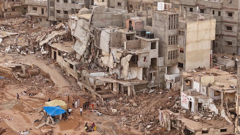 Rescuers and relatives sit in front of collapsed buildings after recent flooding caused by Mediterranean storm Daniel, in Derna, Libya, Monday, Sept. 18, 2023. Derna flood survivor Abdul Salam Anwisi said he woke up at one-thirty in the morning to a loud scream from outside, to find his neighbours&#39; homes flooded with water. He, his sons and other neighbours rushed to rescue the stranded families by pulling them from the roof of their house.(AP Photo/Muhammad J. Elalwany)