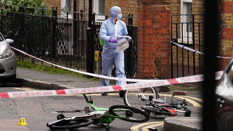 A police forensic officer walks past rental bikes lying in the road near a property in Cranwood Street, central London, where a man died from stab wounds