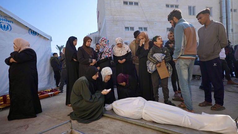 Woman prays over a covered body in Gaza