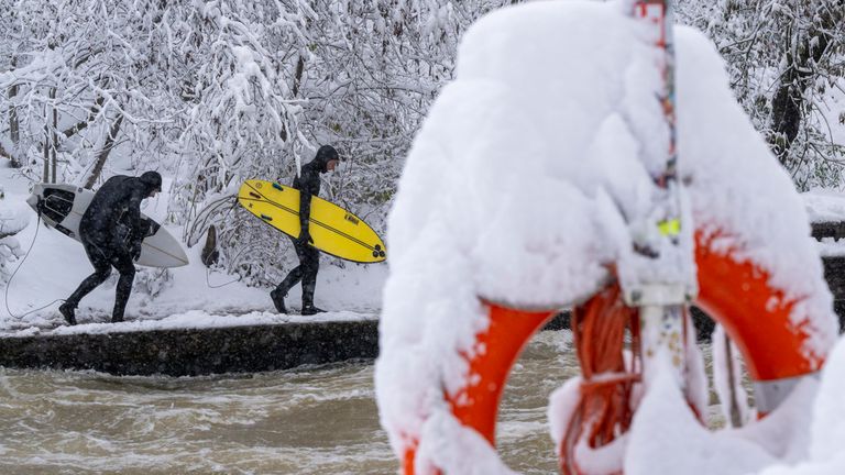 02 December 2023, Bavaria, Munich: Two men walk along the Eisbach in the English Garden with their surfboards in freezing temperatures. Photo by: Peter Kneffel/picture-alliance/dpa/AP Images