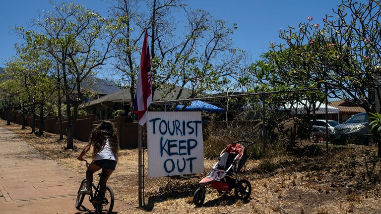 A girl rides her bike past a sign that says &#39;Tourist Keep Out&#39; in Hawaii. Pic: AP