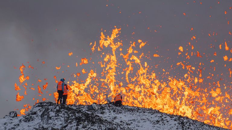 Scientist of the University of Iceland take measurements and samples standing on the ridge in front of the active part of the eruptive fissure of an active volcano in Grindavik on Iceland&#39;s Reykjanes Peninsula, Tuesday, Dec. 19, 2023. (AP Photo/Marco Di Marco)