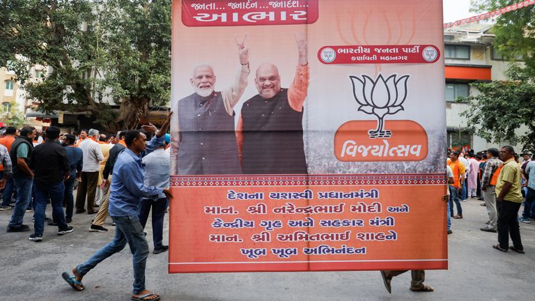 BJP supporters carry a hoarding of Indian Prime Minister Narendra Modi and union minister of home affairs Amit Shah after winning three out of four states in key regional polls outside the party headquarters in Ahmedabad, India
