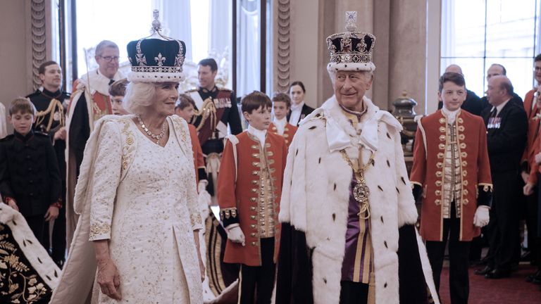 EMBARGOED TO 0001 SUNDAY DECEMBER 17 For use in UK, Ireland or Benelux countries only Undated BBC handout photo of King Charles III and Queen Camilla in Coronation gowns and crowns returning to Buckingham Palace on Coronation day, as seen on the BBC documentary King Charles III: The Coronation Year, which will be broadcast on Boxing Day. Issue date: Sunday December 17, 2023.

