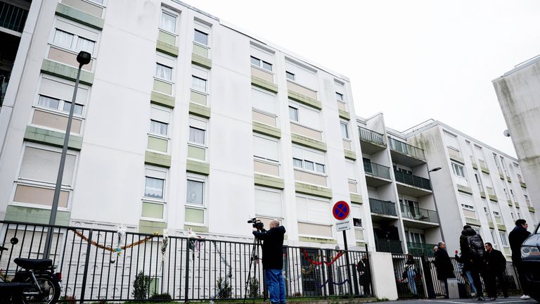 People stand outside the flat where the bodies of a woman and her four children were discovered