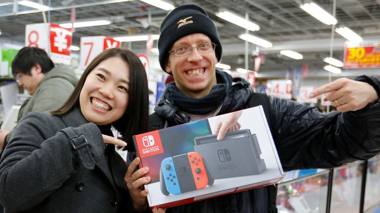 ناو إيموتو (يسار) وزوجها ديفيد فلوريس يقفان مع وحدة التحكم في ألعاب نينتندو سويتش بعد شرائها من متجر إلكترونيات في 3 مارس 2017 في طوكيو، اليابان.  رويترز / تورو هاناي