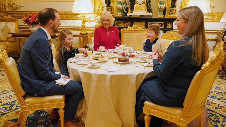 Queen Camilla takes tea with seven-year-old Olivia Taylor from Sidcup along with her sister Imogen, four, (second left), father Matt (left), and mother Lisa (right) at Windsor Castle