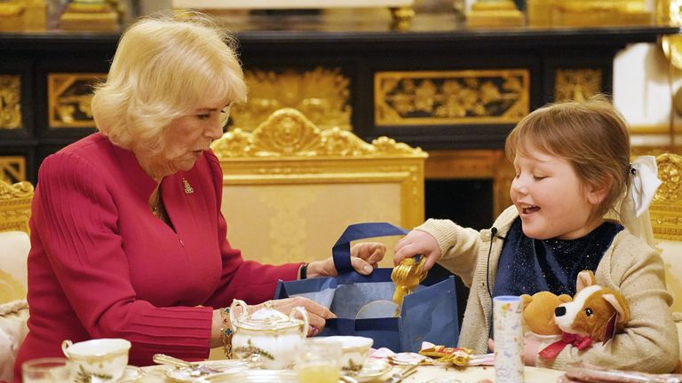 Queen Camilla presents seven-year-old Olivia Taylor from Sidcup with a Christmas presents whilst taking tea at Windsor Castle