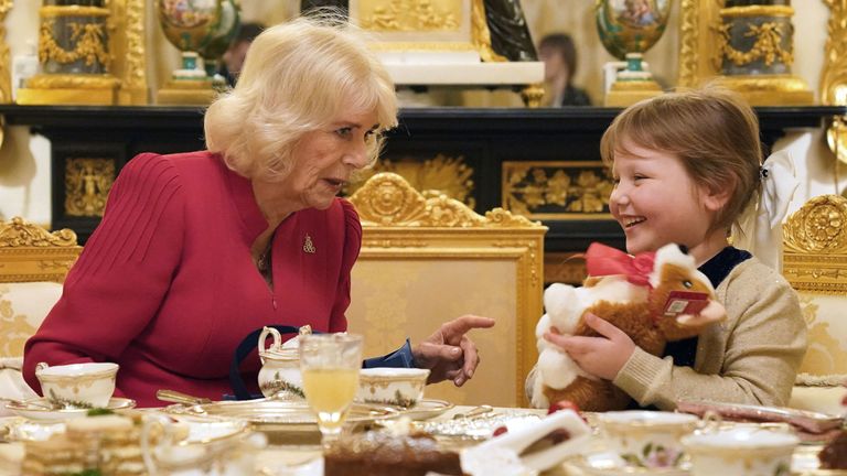 Queen Camilla presents seven-year-old Olivia Taylor from Sidcup with a corgi Christmas present whilst taking tea at Windsor Castle