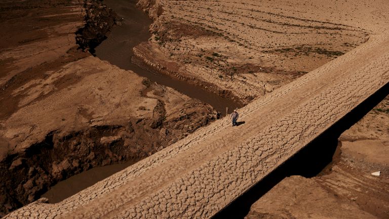 A man walks on the cracked ground of the Baells reservoir as drinking water supplies have plunged to their lowest level since 1990 due to extreme drought in Catalonia, in the village of Cersc, in the region Bergueda, Spain, March 14, 2023.