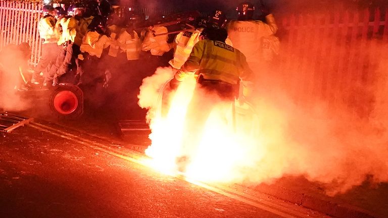 Police attempt to put out flares that have thrown towards them outside the stadium  