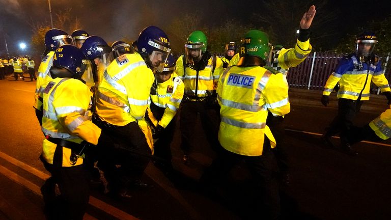 A police officer is helped up by colleagues after being hit by a flare
