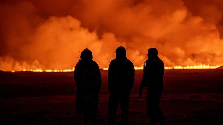 People watch as the night sky is illuminated caused by the eruption of a volcano in Grindavik on Iceland&#39;s Reykjanes Peninsula, Monday, Dec. 18, 2023. (AP Photo/Marco Di Marco)


