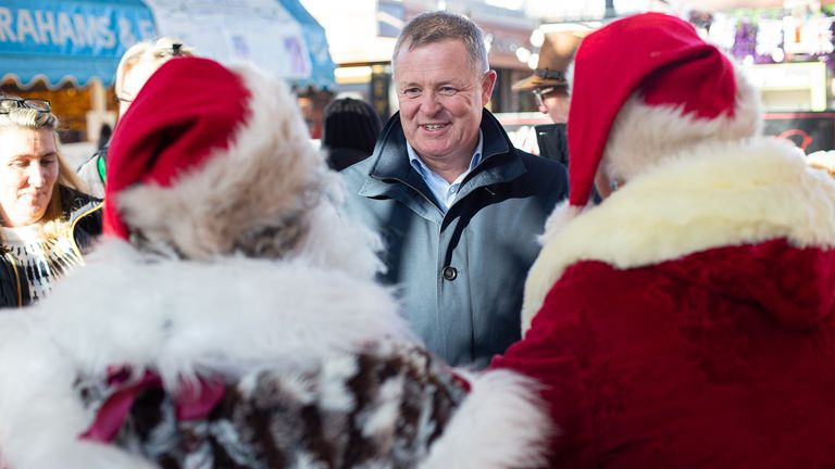 Jeremy Miles speaking with two Santas